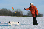 woman plays with Parson Russell Terrier in the snow
