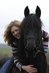 woman rides Frisian horse
