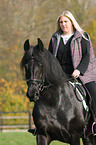 woman rides Frisian horse