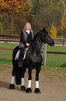 woman rides Frisian horse