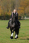 woman rides Frisian horse