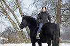 woman rides Frisian horse