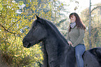 woman rides Frisian horse