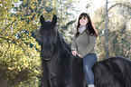 woman rides Frisian horse