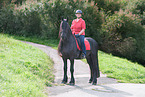 woman rides Friesian Horse