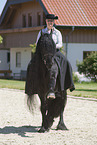 woman rides Friesian horse