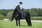 woman rides Friesian horse