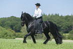 woman rides Friesian horse