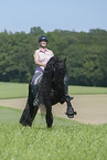 woman rides Friesian horse