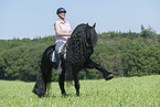 woman rides Friesian horse