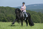 woman rides Friesian horse
