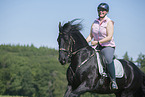 woman rides Friesian horse