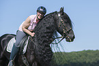 woman rides Friesian horse