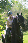 woman rides Friesian horse