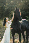young woman in dress with frisian horse