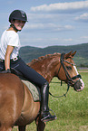 young woman rides German Riding Pony
