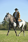 man rides Appaloosa-Mix