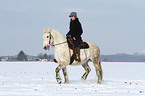 woman rides warmblood in the snow